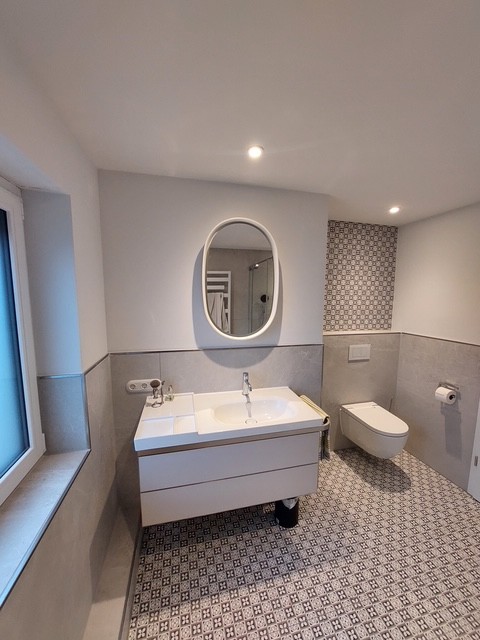 Referenzbild Bad mit hellgrauen Fliesen Bodenfliesen gemustert Waschtisch Toilette