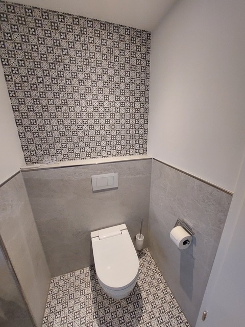 Referenzbild Bad mit hellgrauen Fliesen Bodenfliesen gemustert Toilette in Nische